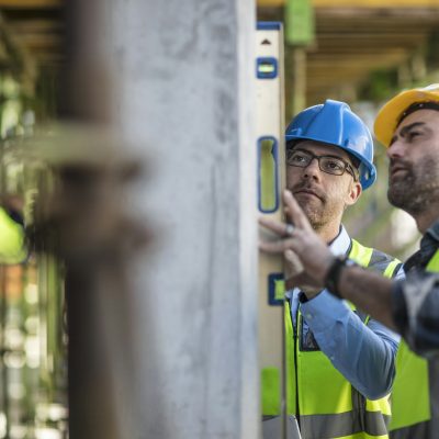 Project manager and construction worker using spirit level